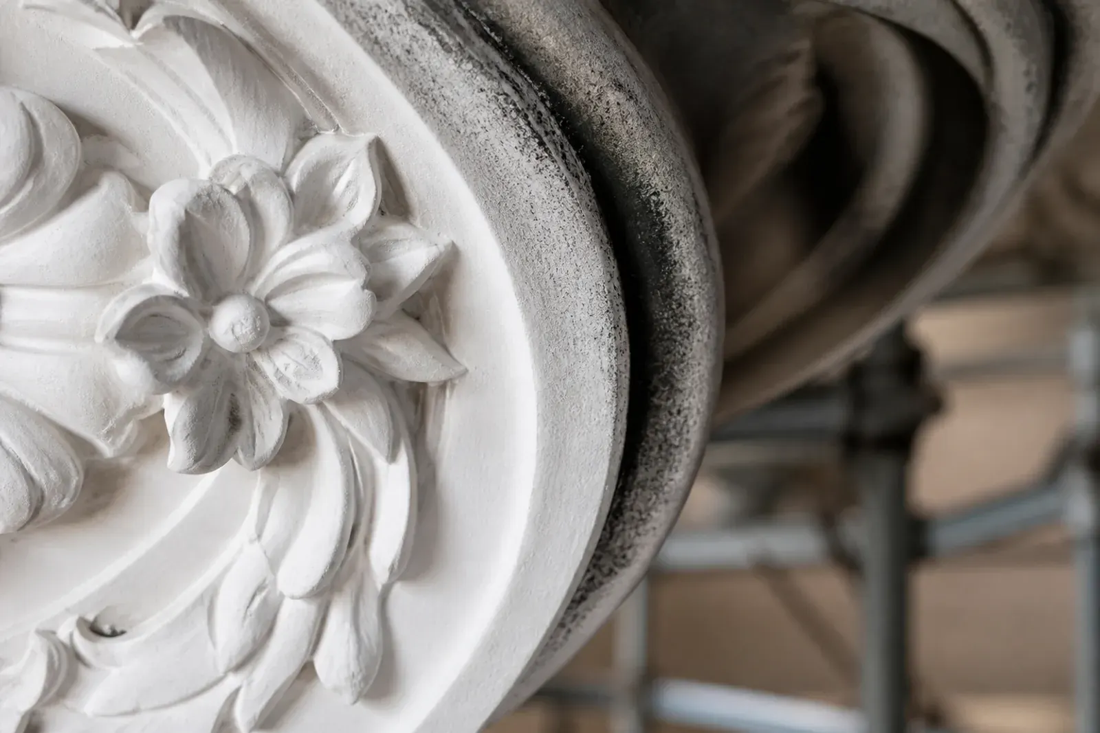 Rosone in stucco annerito dal fumo, con una metà già pulita